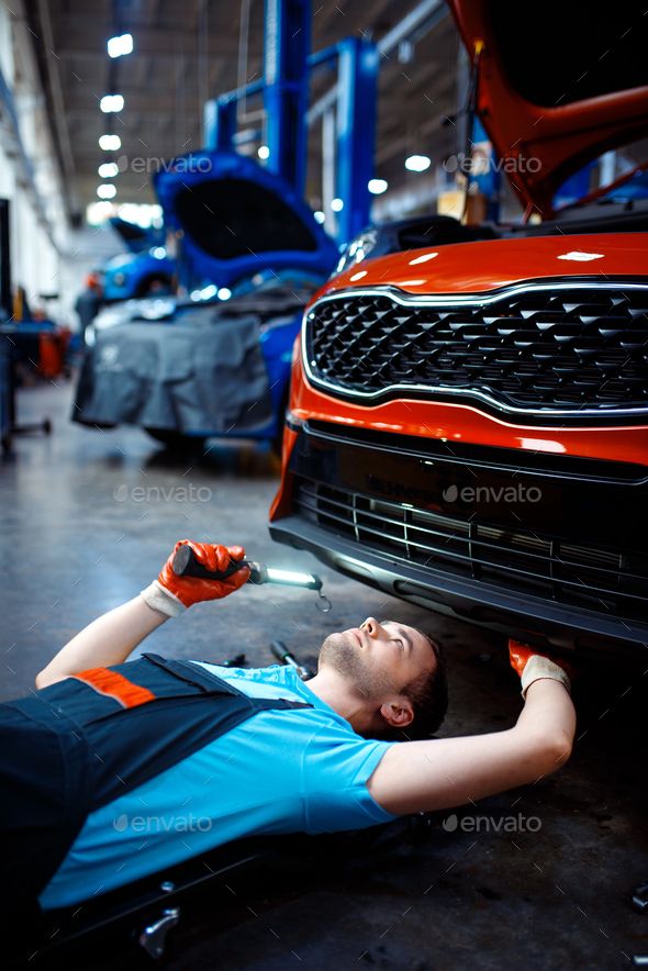 a mechanic working on the front bumper of a car in a garage - stock photo - images