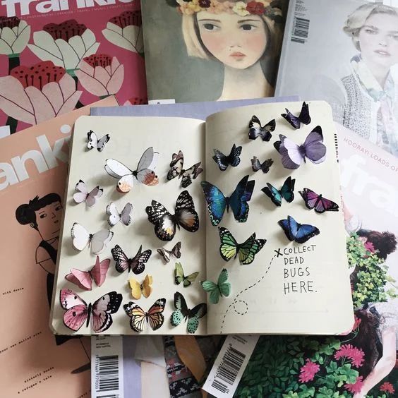 an open book with lots of butterflies on top of it next to magazines and magazines