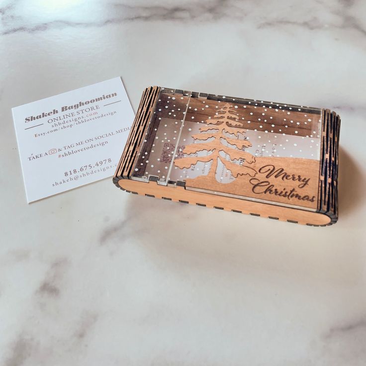 a business card holder sitting on top of a marble counter next to a christmas tree