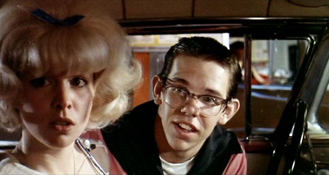 a man and woman sitting in the back seat of a car looking at each other