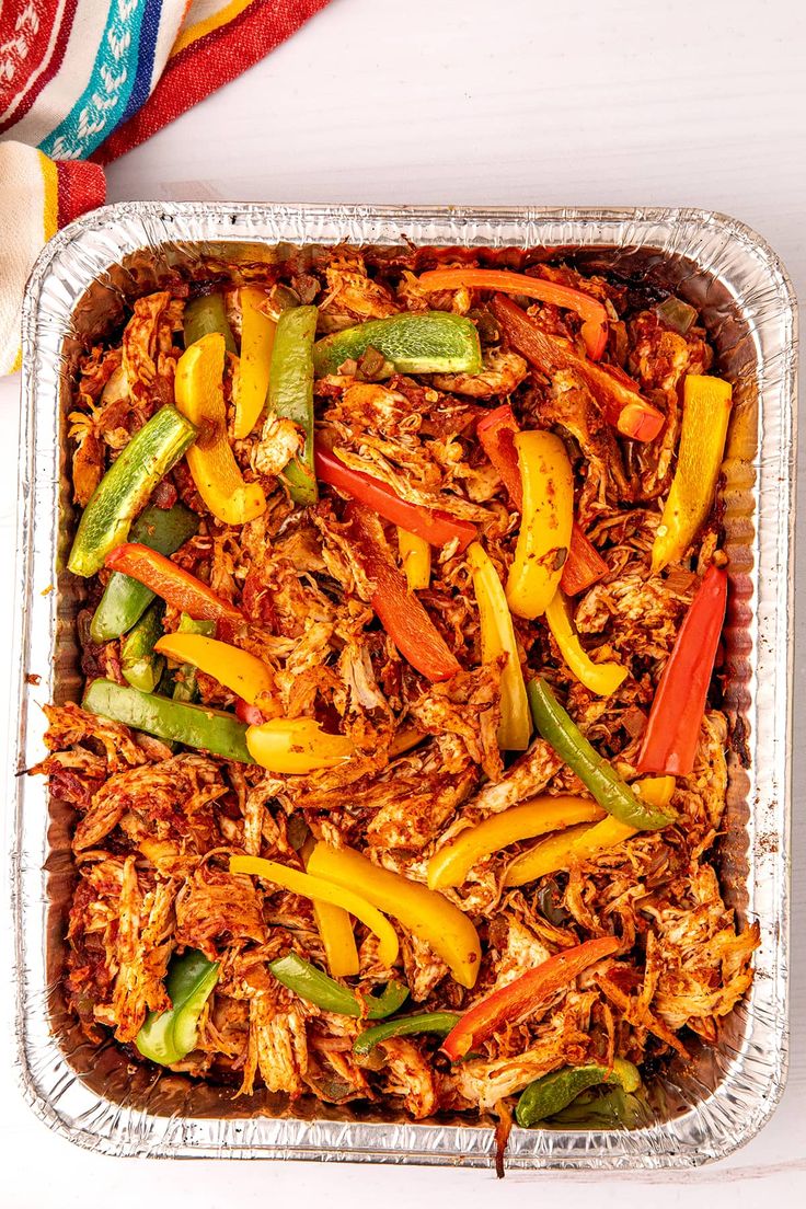 a casserole dish with meat and vegetables in it on a white tablecloth