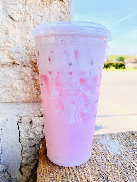 a pink drink sitting on top of a wooden table