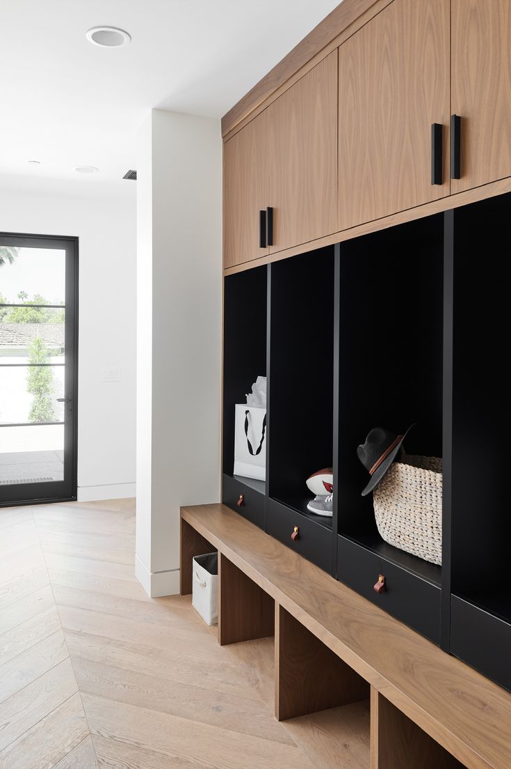 an empty room with wooden cabinets and black doors, along with a white basket on the wall