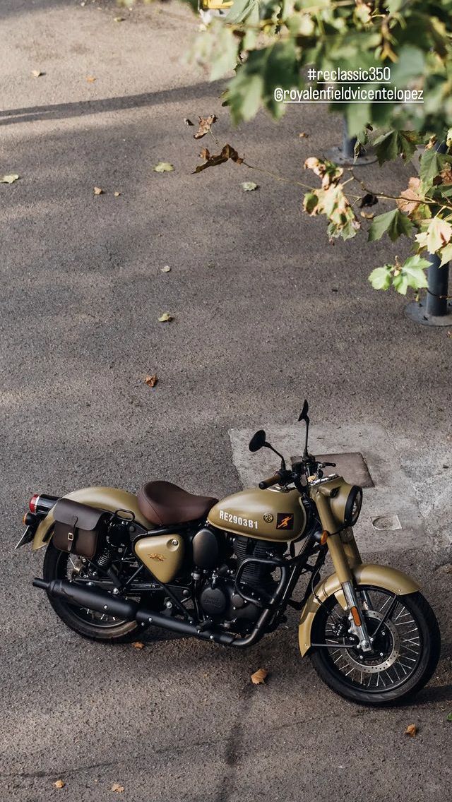 a motorcycle is parked on the street in front of some bushes and trees with leaves