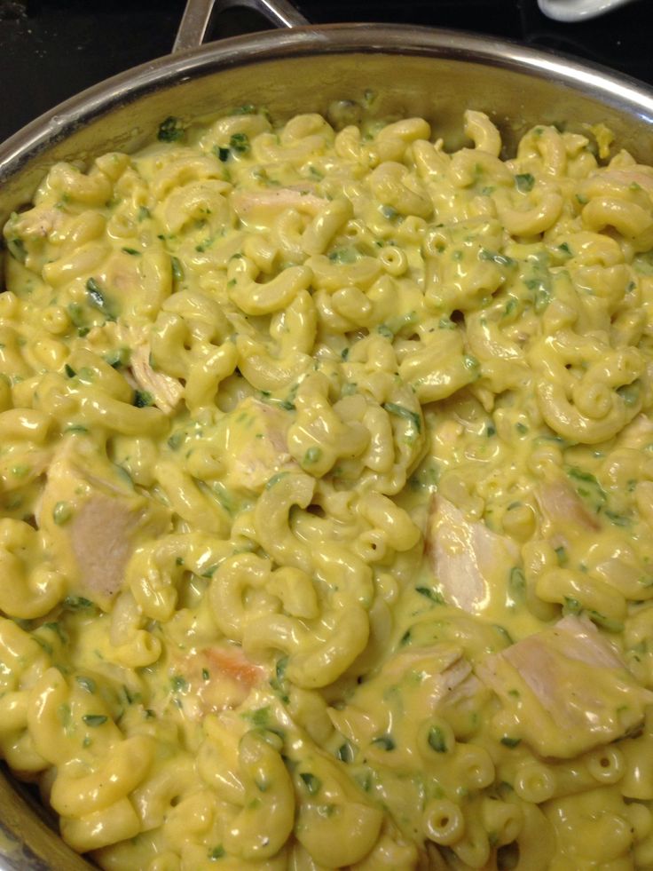 macaroni and cheese with chicken is in a pan on the stove top, ready to be cooked