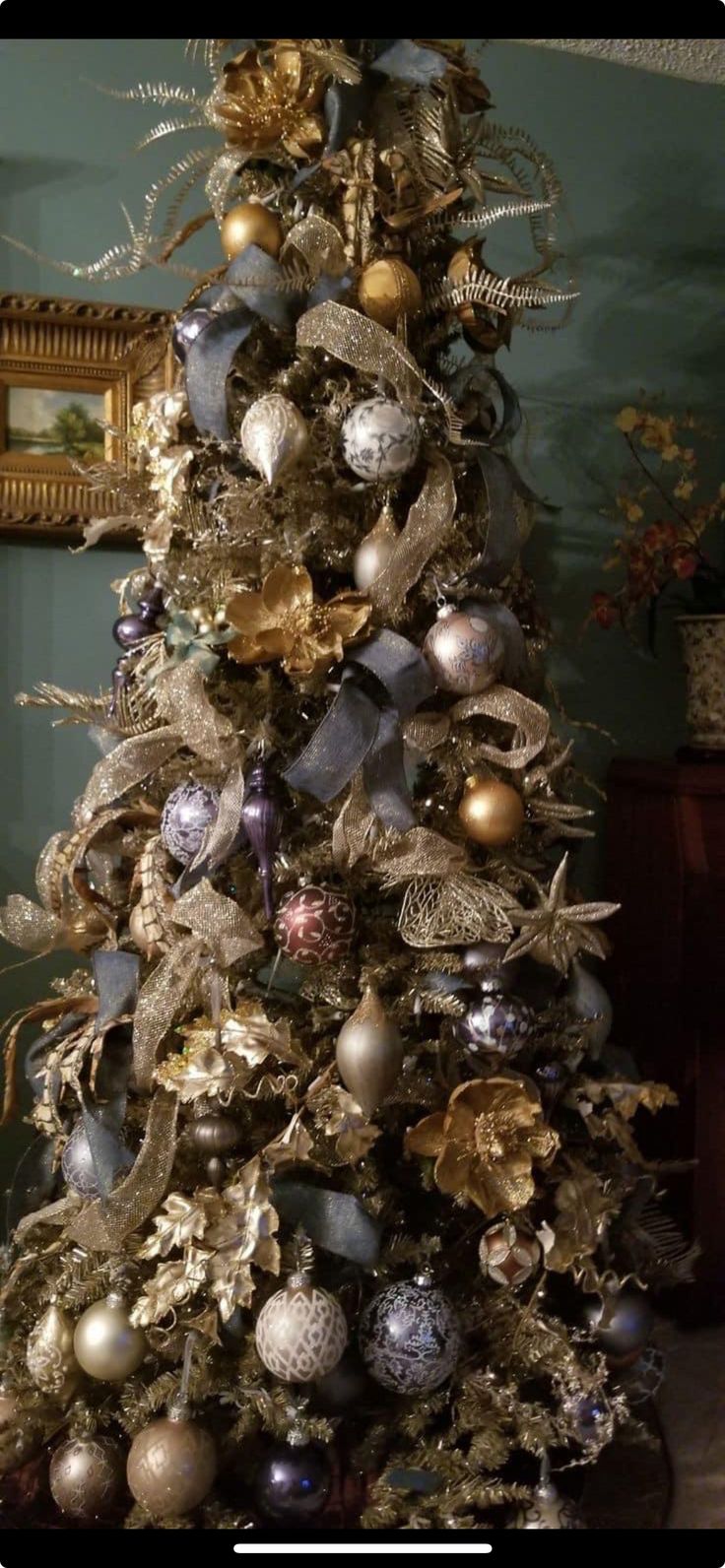 a decorated christmas tree with ornaments on it's branches and gold, silver and blue decorations