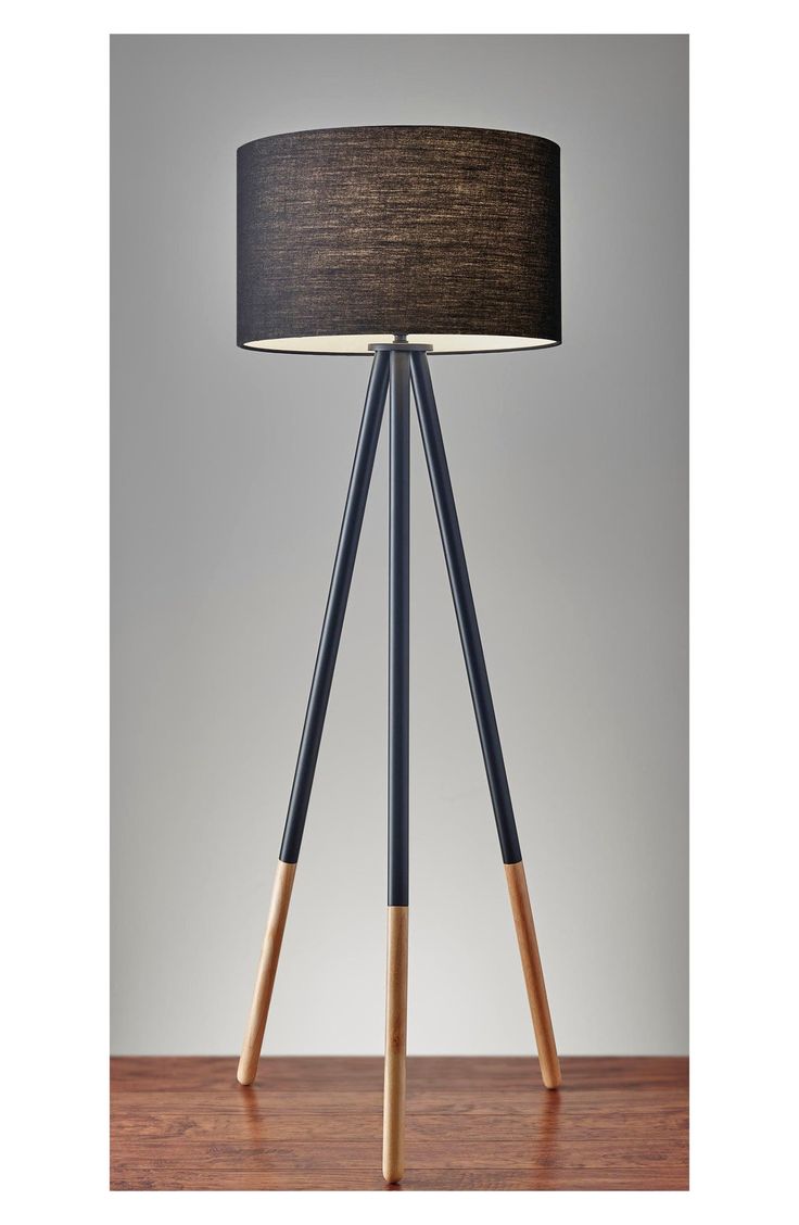 a lamp that is sitting on top of a wooden table with a black shade over it