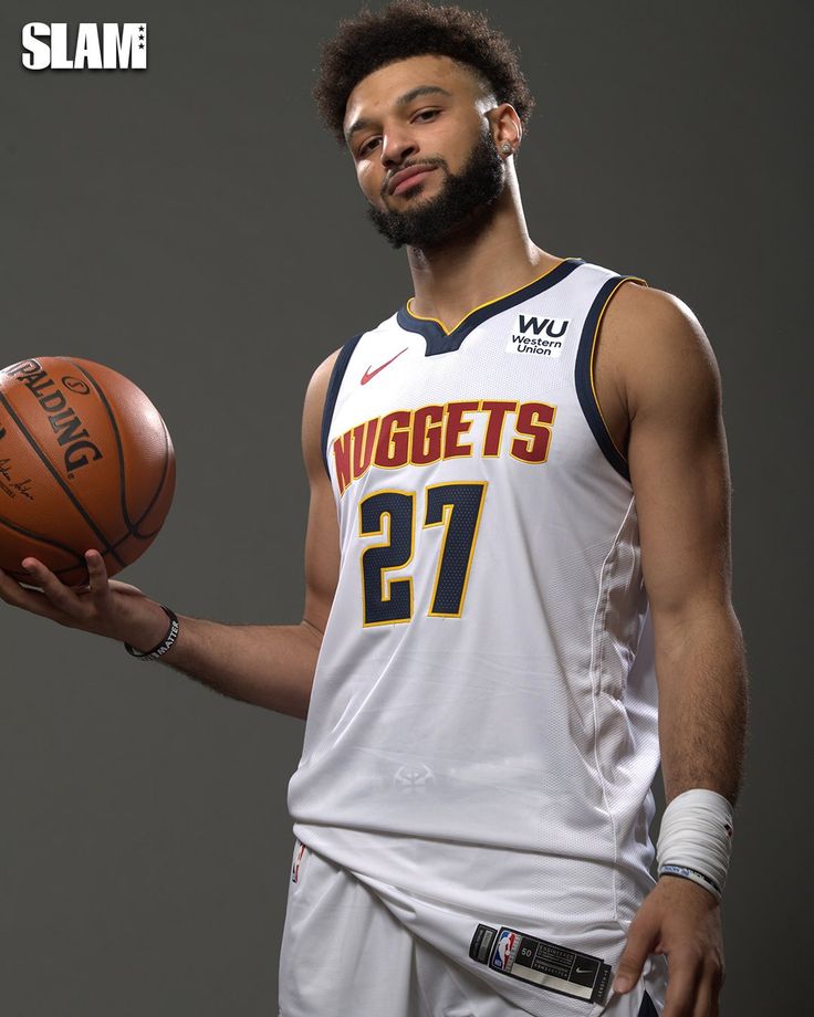 a man holding a basketball in his right hand and wearing a white uniform with the number 27 on it