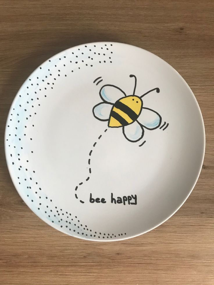 a plate with a drawing of a bee on it that says be happy in the center