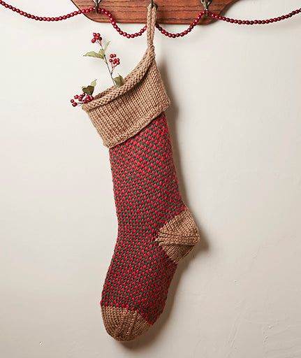 a christmas stocking hanging on the wall with red and white knitted stockings attached to it