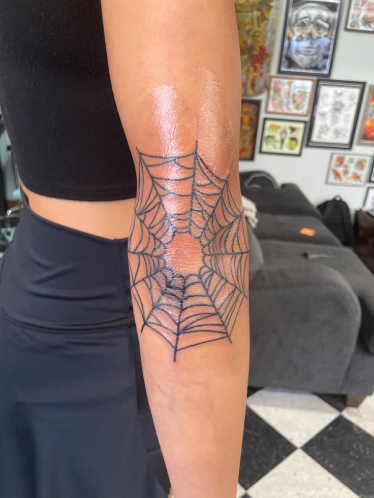 a woman with a spider web tattoo on her arm