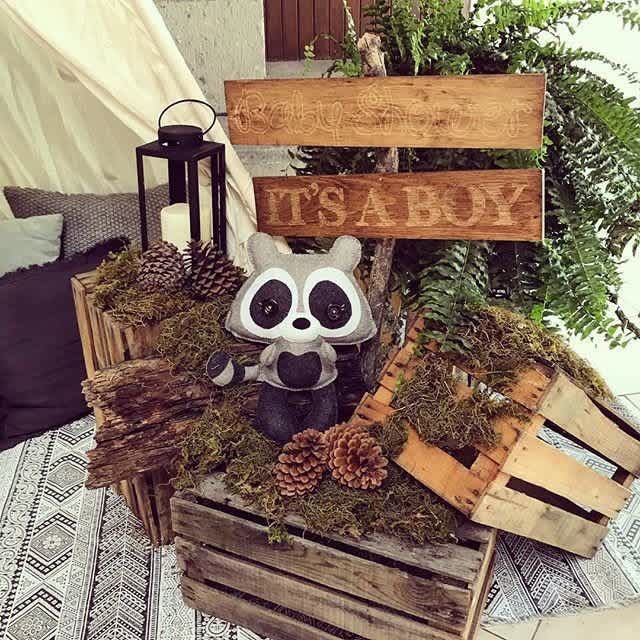 a stuffed raccoon sitting on top of a wooden crate filled with pine cones