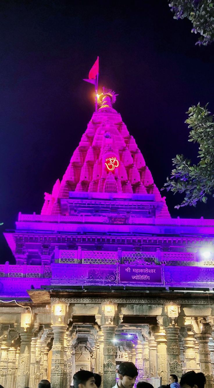 people are standing in front of a temple at night