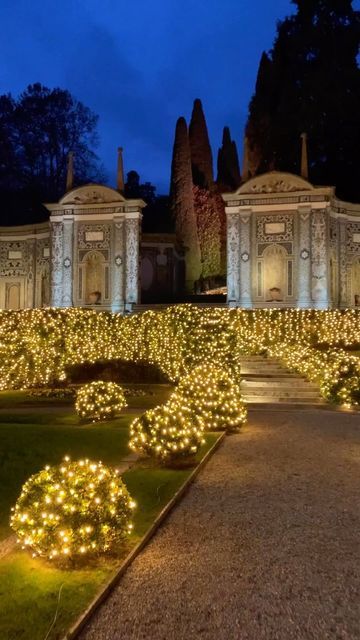 the garden is lit up at night with lights on it and trees in the background