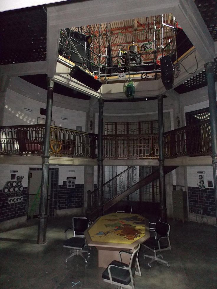 an empty room with several chairs and tables in front of a staircase that leads up to the second floor