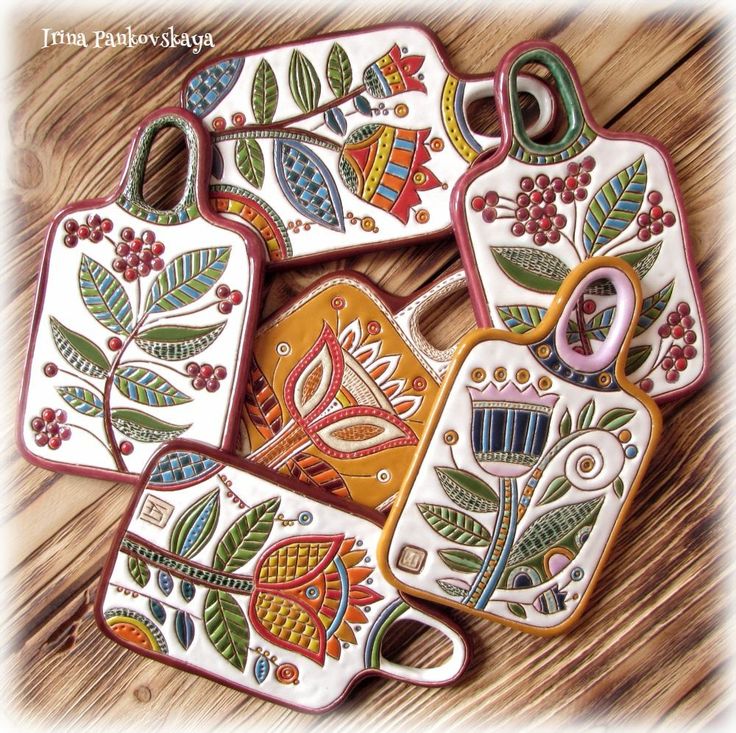 four hand painted ceramic tags with flowers and leaves on them, sitting on a wooden surface