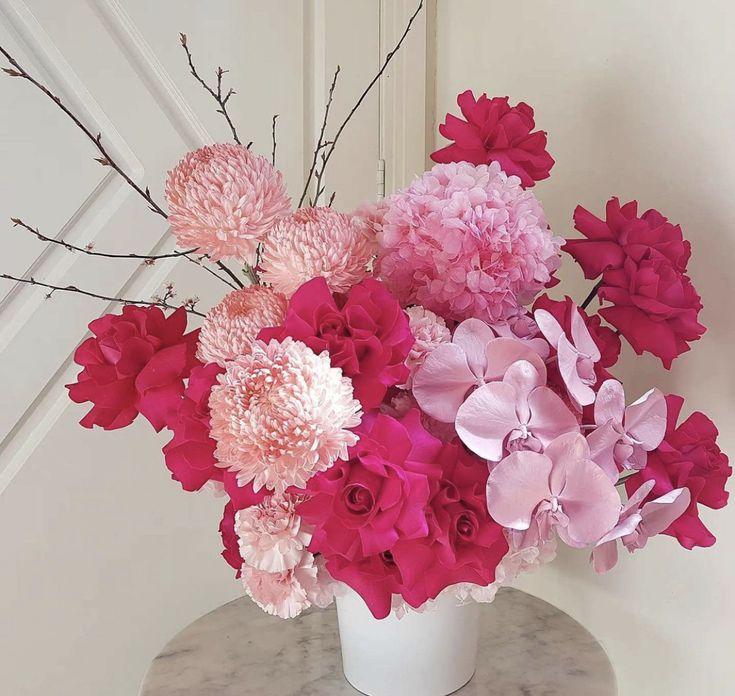 a white vase filled with pink and red flowers