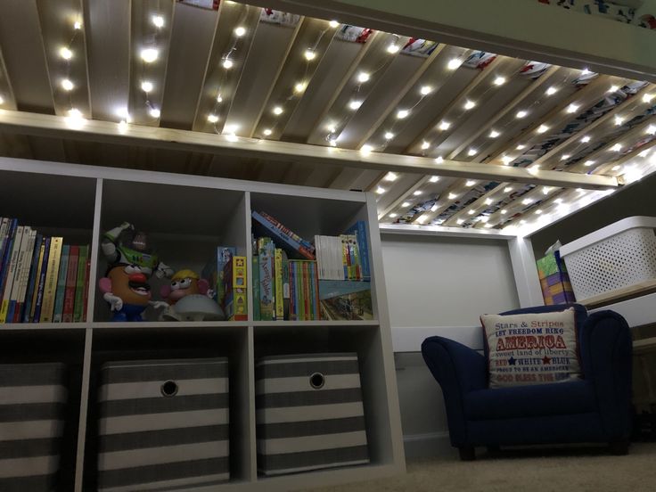 a blue chair sitting in front of a book shelf filled with lots of books and toys