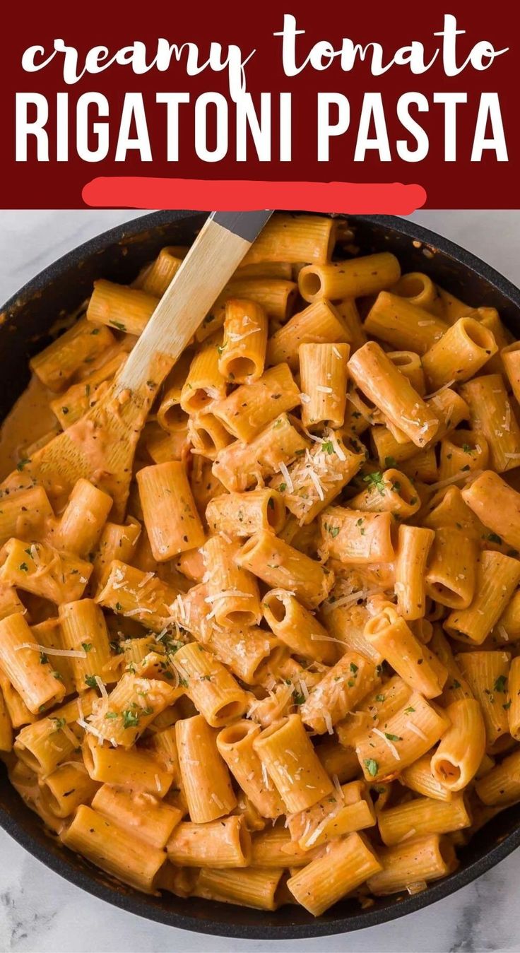 creamy tomato rigatoni pasta in a skillet with a wooden spoon on the side