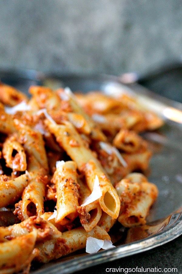 a plate full of pasta with sauce and cheese on the top is ready to be eaten