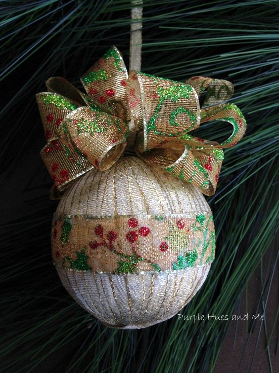 an ornament hanging from a pine tree with a bow on it's side