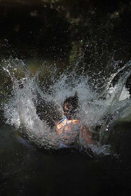 a person falling into the water with their arms out and head in the air as it splashes