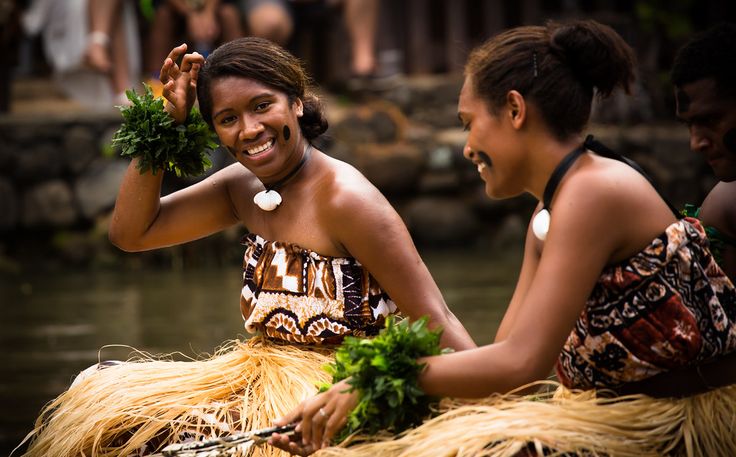 two women in grass skirts sitting on the back of a boat with hula skirt around their waist