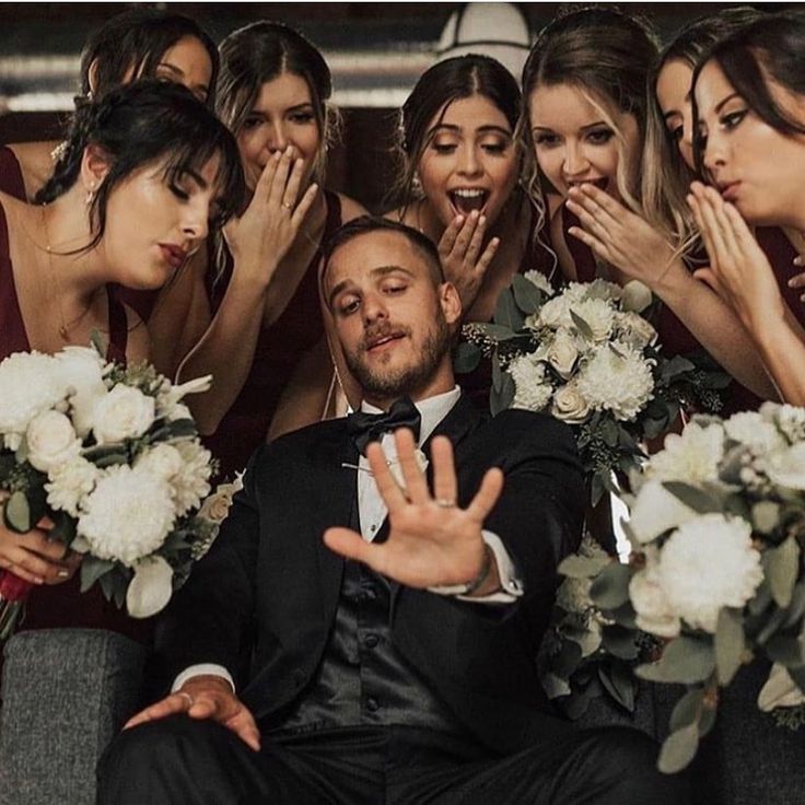 a group of bridesmaids and groomsmid posing for a photo with their hands in the air