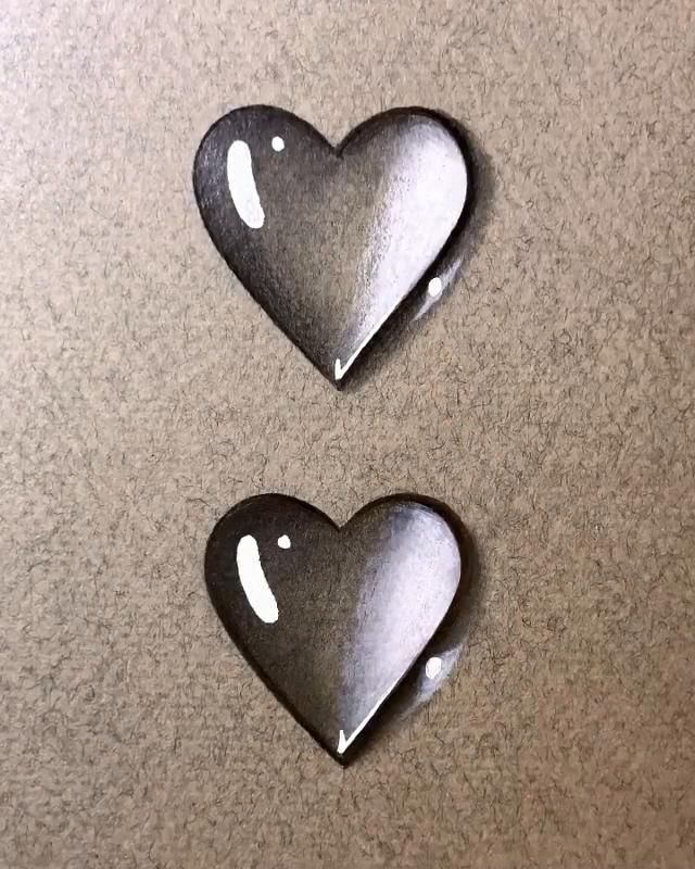 two metal heart shaped magnets sitting on top of a table next to each other