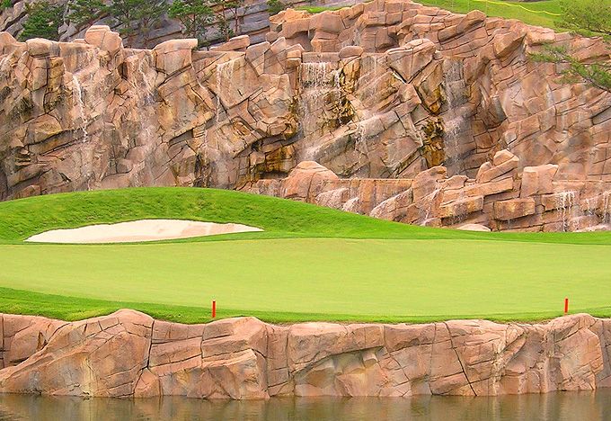 a golf course with water and large rocks