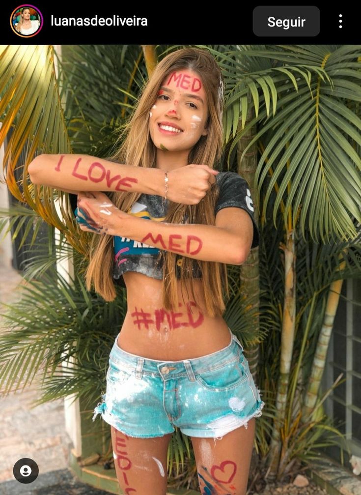 a girl with painted words on her body is posing in front of some palm trees