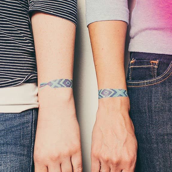 two people with matching wristbands standing next to each other and holding hands together