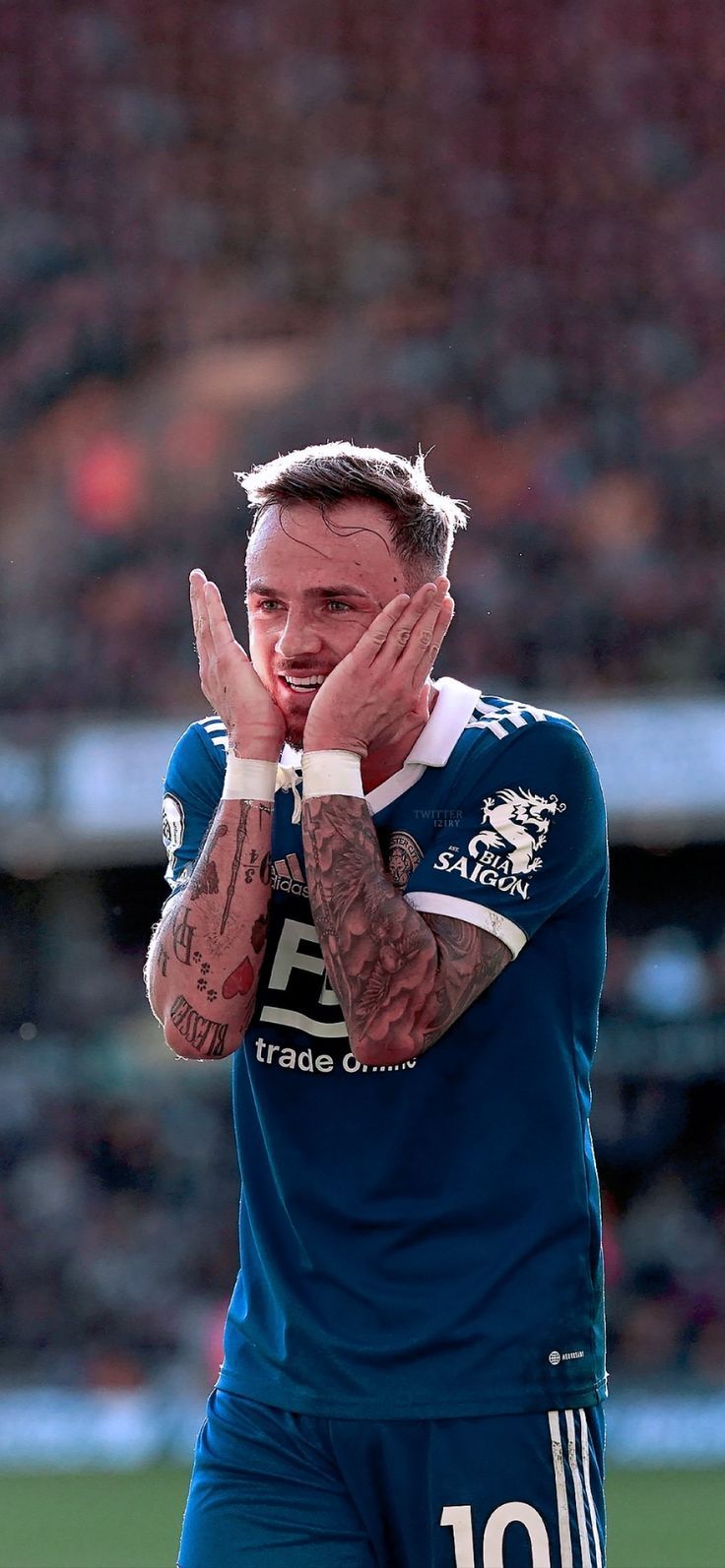 a man with tattoos on his arms and chest standing in front of a soccer field