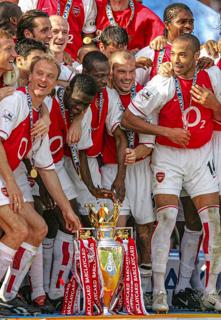 a group of men standing next to each other in front of a soccer trophy on top of a field