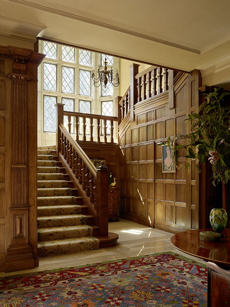 a staircase leading up to the second floor in a large wooden house with stained glass windows