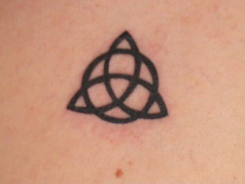 a small tattoo on the back of a woman's upper arm, with a triangle in the middle