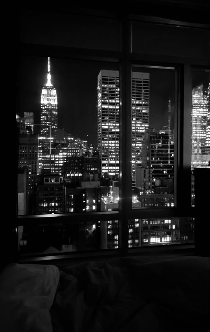 black and white photograph of the city at night from a hotel room in new york