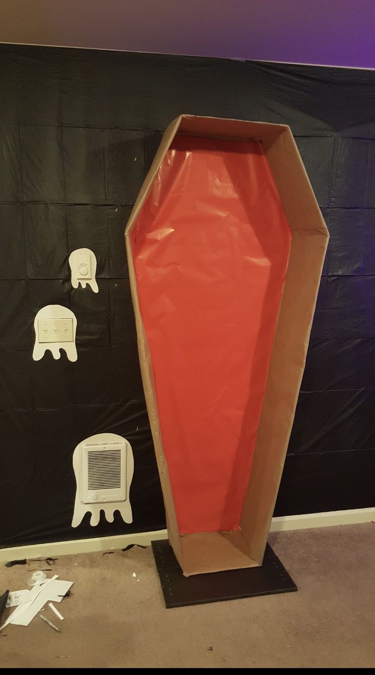 a large red vase sitting on top of a black stand in front of a wall