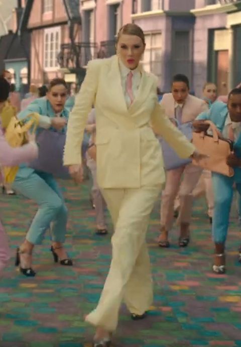 a group of people in suits and ties dancing on a carpeted area with buildings behind them