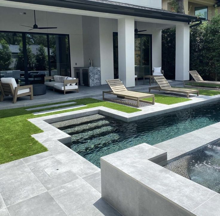 an outdoor pool with lounge chairs and artificial grass