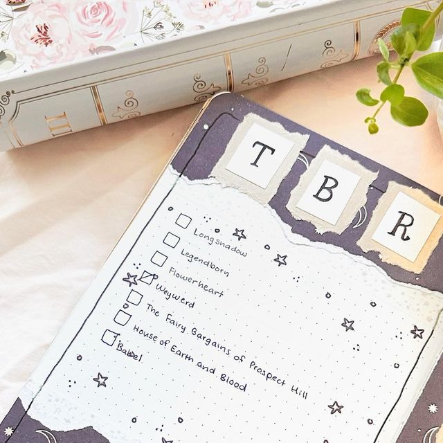 a binder with the word tbr written on it next to a flower pot