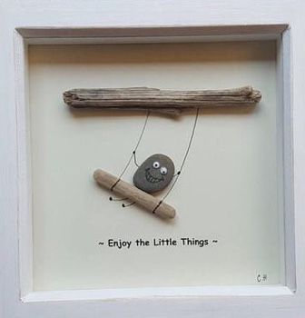 an image of a rock and wooden stick in a shadow box with the words enjoy the little things written on it