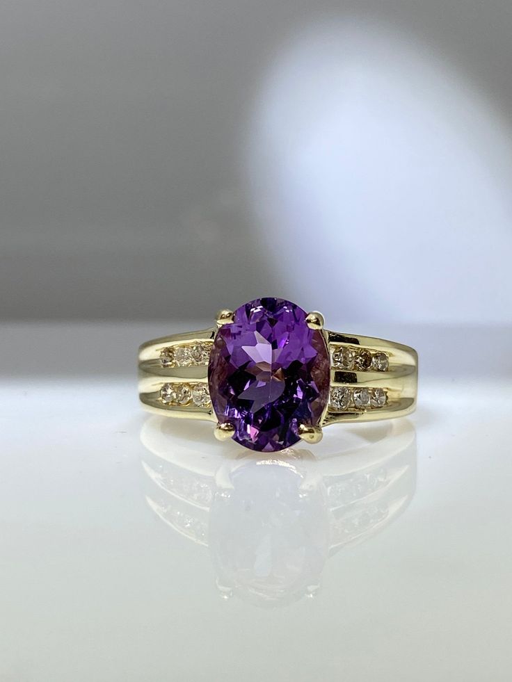 14K yellow gold ring with genuine amethyst and diamonds. The amethyst is oval shaped and weighs about 4.00 carats. It has a super rich royal purple hue and is clean of inclusions. There are two rows of channel set diamonds on each side of the amethyst. The total diamond weight is about 0.20 carats. The ring has a nice thick shank and is ready to wear everyday. Finger size is 7 Feel free to message me if you have any other questions. Oval Amethyst Ring With Gemstone Accents For Formal Occasions, Classic Oval Amethyst Ring With Diamond, Classic Oval Amethyst Ring With Accent Stones, Oval Brilliant Cut Amethyst Ring In Yellow Gold, Classic Oval Purple Amethyst Ring, Oval Purple Amethyst Ring For Formal Occasions, Timeless Oval Purple Amethyst Ring, Oval Purple Amethyst Ring With Center Stone, Timeless Purple Oval Amethyst Ring