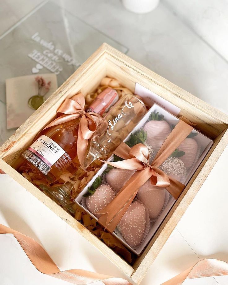 two bottles of booze in a wooden box with ribbon around the edges and inside