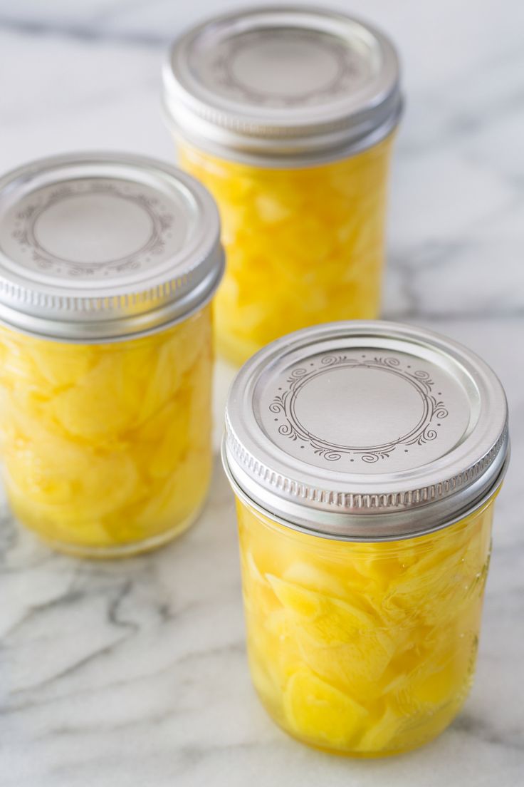 three jars filled with yellow food sitting on top of a marble counter