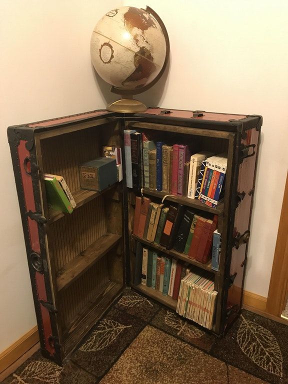 an old bookcase with a globe on top and books in the bottom, sitting next to a wall