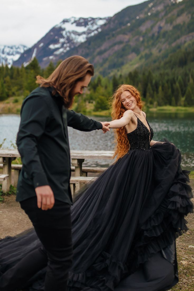 a woman in a black dress standing next to a man