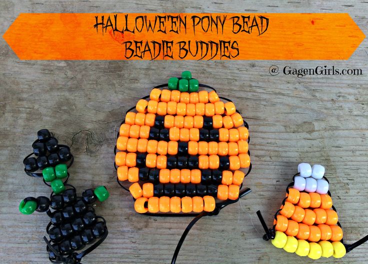 three halloween beaded pumpkins sitting next to each other on a wooden table with an orange and black sign