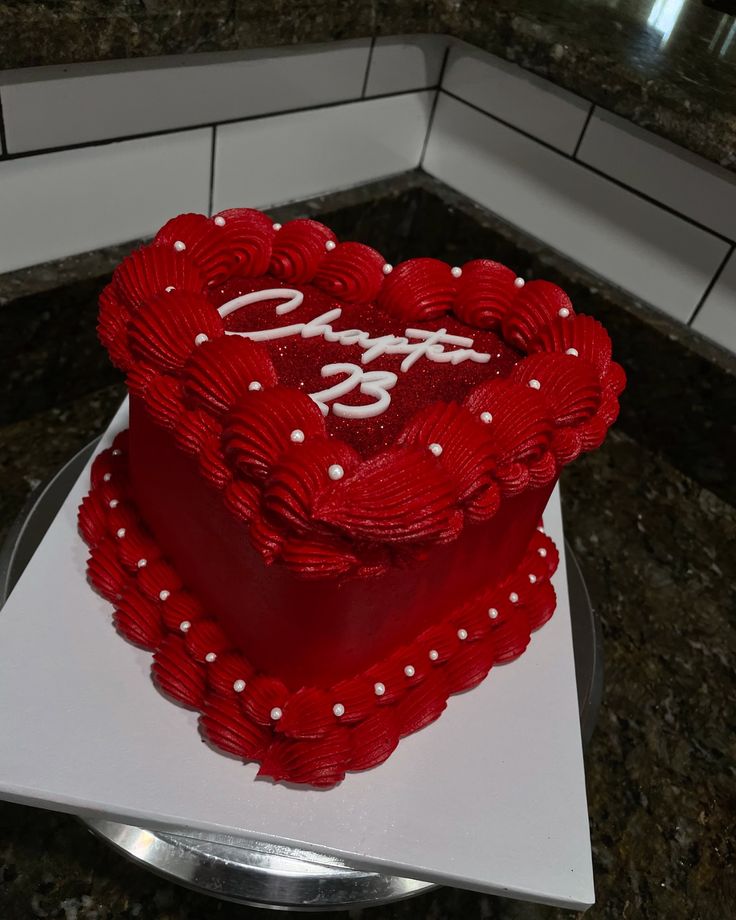 a red heart shaped cake sitting on top of a counter