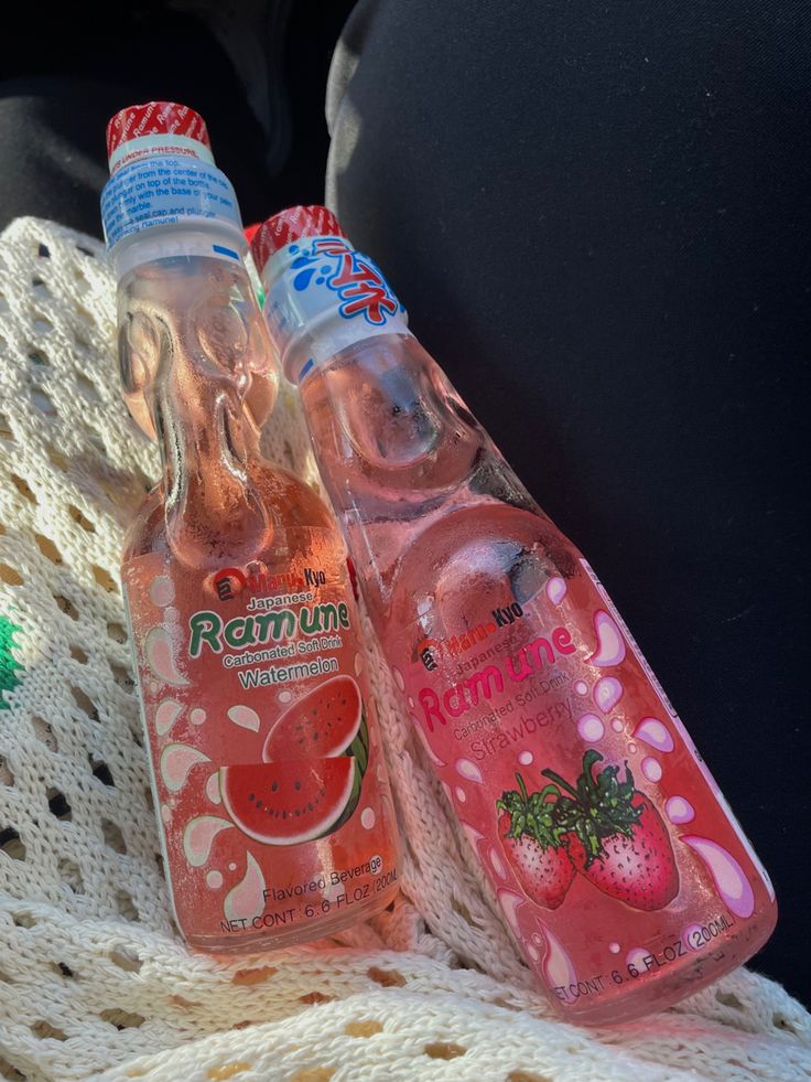 two bottles of water sitting next to each other on a white knitted blanket in the back seat of a car